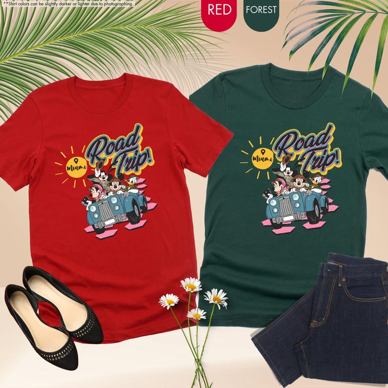 Op de afbeelding: Rode en bosgroene t-shirts met een cartoonafbeelding van Mickey Mouse en vrienden in een auto, met de tekst "Road Trip!". Zwarte ballerina's en een blauwe jeans zijn ook in de afbeelding.