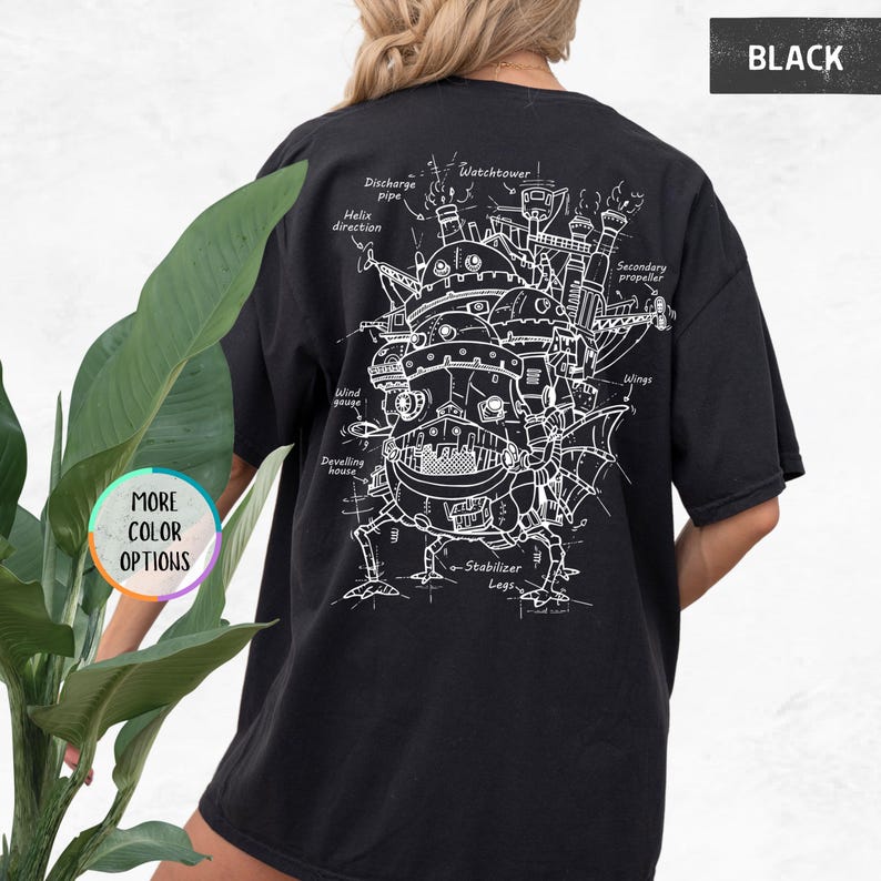 Op de afbeelding: Zwart t-shirt met een witte technische tekening van een fantasiegebouw, met opschriften als "Watchtower" en "Stabilizer Legs". Het shirt heeft ook de tekst "BLACK" en "MORE COLOR OPTIONS".