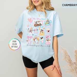 May include: Light blue t-shirt featuring a colorful collage of Disney characters and icons, including Mickey Mouse, Donald Duck, and Dumbo. The shirt has the text "Walt Disney World" and "The Most Magical Place on Earth".