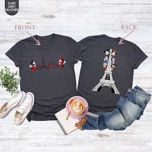 Pu&ograve; includere: T-shirt grigio scuro con un design frontale con la Torre Eiffel e la scritta "Paris" con Topolino e Minnie. Il retro della maglietta presenta un design della Torre Eiffel con personaggi Disney. Le magliette sono esposte con jeans e scarpe da ginnastica.