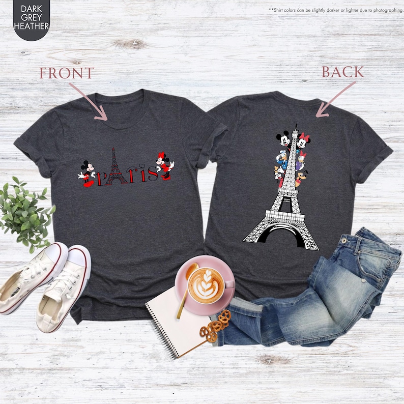 Pu&ograve; includere: T-shirt grigio scuro con un design frontale con la Torre Eiffel e la scritta "Paris" con Topolino e Minnie. Il retro della maglietta presenta un design della Torre Eiffel con personaggi Disney. Le magliette sono esposte con jeans e scarpe da ginnastica.