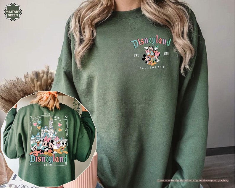 May include: A green sweatshirt with a Disneyland logo featuring Mickey Mouse and friends. The logo says "Disneyland Est. 1955 California".