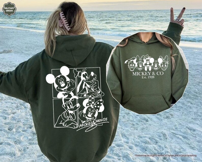 Pu&ograve; includere: Felpa con cappuccio verde militare con grafica bianca di Topolino, Pippo, Minnie e Paperino. Il retro presenta un design a quattro pannelli con Topolino e Minnie. Il davanti ha la scritta "MICKEY & CO Est. 1928".