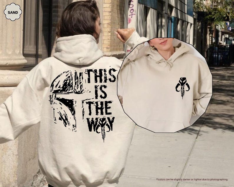 May include: A beige hoodie with a black graphic print of a Mandalorian helmet and the text "This is the Way".