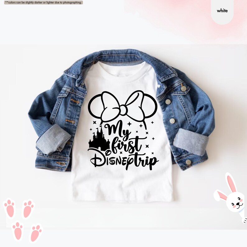 Pu&ograve; includere: Maglietta bianca con una grafica nera di orecchie di Topolino con un fiocco, un castello e il testo "My first DISNEptrip".
