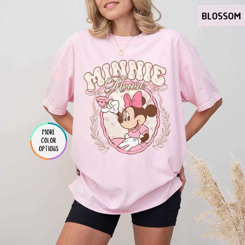 May include: Pink t-shirt with a vintage-style graphic of Minnie Mouse holding a teacup. The graphic features the text "Minnie Mouse" in a floral design.