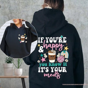 a woman wearing a black hoodie with a picture of a cup of coffee on