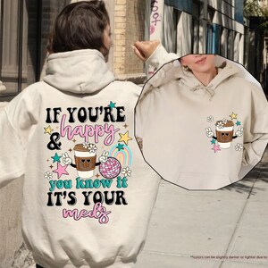 a person wearing a white hoodie with a cup of coffee on it