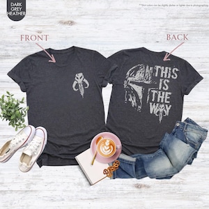 Pu&ograve; includere: Una t-shirt grigio scuro melange con una grafica di casco di Mandaloriano sul retro. Il testo "This is the way" &egrave; stampato sul retro della t-shirt. La parte anteriore della t-shirt ha una piccola grafica di simbolo Mandaloriano.