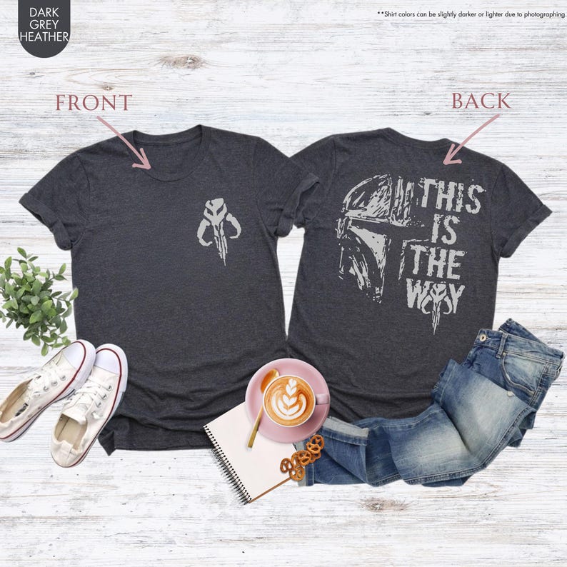 Pu&ograve; includere: Una t-shirt grigio scuro melange con una grafica di casco di Mandaloriano sul retro. Il testo "This is the way" &egrave; stampato sul retro della t-shirt. La parte anteriore della t-shirt ha una piccola grafica di simbolo Mandaloriano.