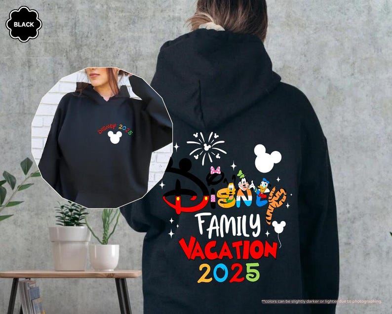 K&ouml;nnte beinhalten: Schwarzer Kapuzenpullover mit einem bunten Disney Family Vacation 2025-Motiv mit Mickey Mouse und anderen Disney-Charakteren. Das Motiv enth&auml;lt auch Feuerwerk und eine Mickey-Mouse-Ohrensilhouette.