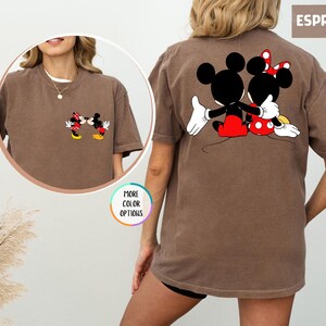 May include: Espresso-coloured t-shirt featuring Mickey and Minnie Mouse. The front of the shirt shows the characters kissing, while the back displays them embracing. The shirt has a classic, relaxed fit and is a comfortable choice for casual wear.