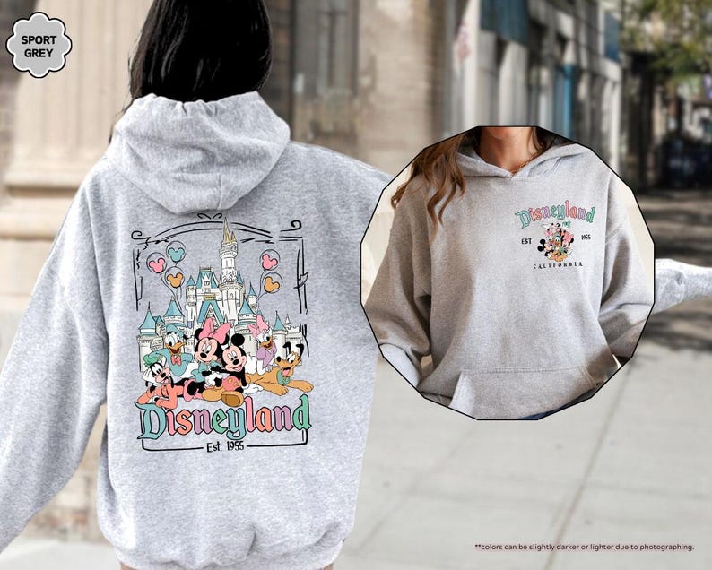 May include: A gray hooded sweatshirt with a graphic print of Mickey Mouse and friends in front of the Disneyland castle. The text "Disneyland Est. 1955" is printed below the graphic.