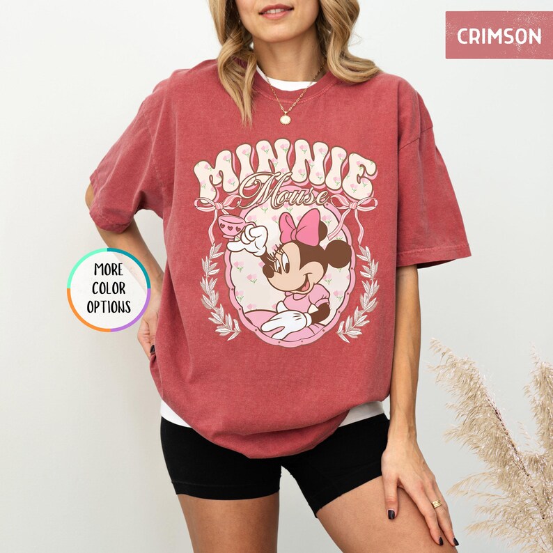 May include: A red t-shirt with a vintage-style graphic of Minnie Mouse holding a teacup. The graphic features the text "Minnie Mouse" in a retro font.