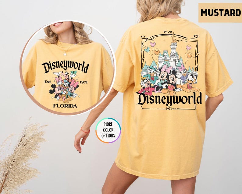 Puede incluir: Camiseta color mostaza con el texto "Disneyworld" y un gr&aacute;fico de personajes de Disney. La parte delantera muestra "Disneyworld Est. 1971 Florida" con personajes de Disney. La parte trasera tiene un gr&aacute;fico m&aacute;s grande de personajes de Disney y "Disneyworld 1971".