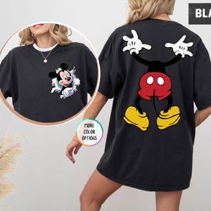 May include: Black t-shirt with a Mickey Mouse design. The front has Mickey emerging from a torn hole, and the back features a full cartoon image of Mickey Mouse with raised arms. The word "BLACK" is printed on the top right of the shirt.