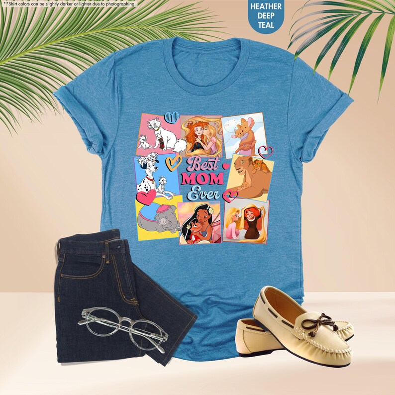 Pode incluir: Uma camiseta azul com uma colagem de princesas Disney e animais. O texto "Best Mom Ever" est&aacute; em letras rosa e brancas com cora&ccedil;&otilde;es de cada lado.
