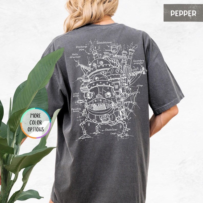 Op de afbeelding: Pepperkleurig T-shirt met een gedetailleerde witte schematische weergave van een fantastisch bewegend kasteel. Het ontwerp bevat labels zoals "Watchtower", "Wind gauge" en "Stabilizer Legs". Het shirt heeft een relaxte pasvorm en is comfortabel.