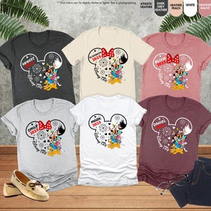 May include: Six t-shirts with a Mickey Mouse head design. Each shirt has a different name and the year 2023 printed on it. The shirts are in various colors, including gray, white, and maroon.