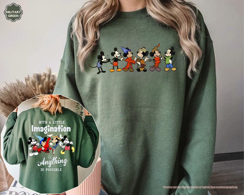 Puede incluir: Sudadera verde militar con una fila de personajes de dibujos animados en el pecho. La parte trasera de la sudadera muestra el texto "WITH A LITTLE IMAGINATION ANYTHING IS POSSIBLE" con un gr&aacute;fico de dibujos animados a juego. La sudadera es de color s&oacute;lido.