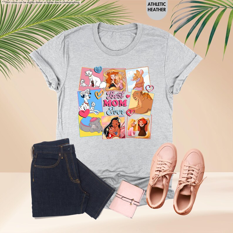 Pode incluir: Camiseta cinza com uma colagem de personagens da Disney e o texto "Best Mom Ever" em letras rosa, azul e amarelo.