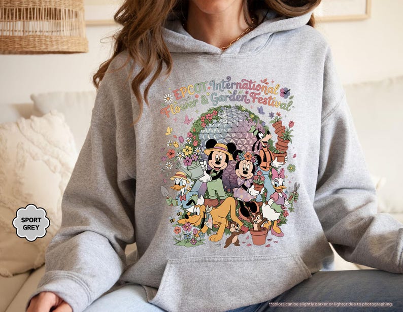 May include: Sport grey hoodie featuring a colorful graphic of Disney characters, including Mickey and Minnie Mouse, surrounded by flowers and the text "EPCOT International Flower & Garden Festival."