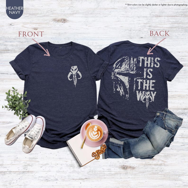 Pu&ograve; includere: Una t-shirt blu navy con una grafica bianca di un elmetto Mandaloriano sul retro e il testo "This is the way". La parte anteriore della t-shirt ha una grafica bianca del simbolo Mandaloriano.