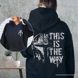 May include: Black hooded sweatshirt with a white graphic of a Mandalorian helmet and the text "This is the Way".