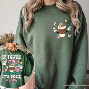 a woman wearing a green sweatshirt with a cup of coffee on it