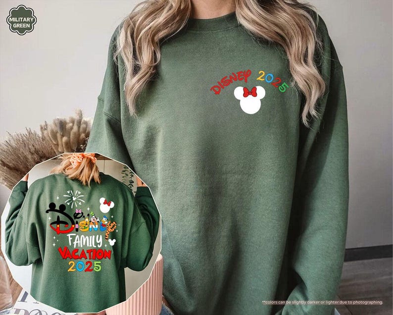K&ouml;nnte beinhalten: Ein gr&uuml;ner Pullover mit dem Text "DISNEY 2025" und einem Mickey Mouse Kopf mit einer roten Schleife. Der Pullover zeigt auch eine kleinere Grafik von Mickey Mouse und anderen Disney-Charakteren mit dem Text "FAMILY VACATION 2025".