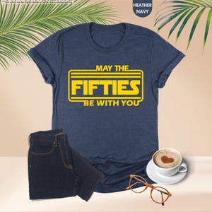 May include: A navy blue t-shirt with a yellow graphic that says "May the Fifties Be With You".
