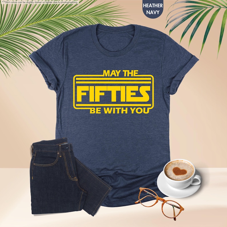 May include: A navy blue t-shirt with a yellow graphic that says "May the Fifties Be With You".