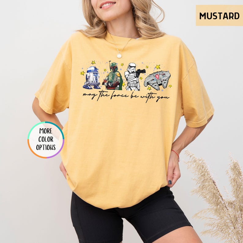 Puede incluir: Camiseta color mostaza con un gr&aacute;fico de Star Wars. El dise&ntilde;o incluye a R2-D2, Boba Fett, un Stormtrooper y el Halc&oacute;n Milenario, con el texto "may the force be with you".