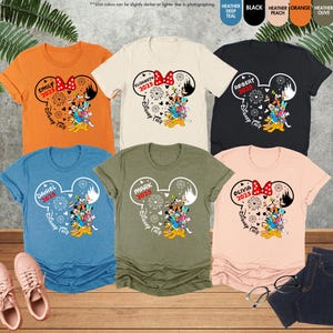 May include: Six different colored t-shirts with a Mickey Mouse design and the text "Disney Trip 2025" on each shirt. The shirts are in the colors orange, beige, black, blue, green, and peach.