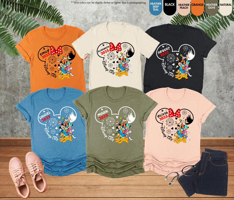 May include: Six different colored t-shirts with a Mickey Mouse design and the text "Disney Trip 2025" on each shirt. The shirts are in the colors orange, beige, black, blue, green, and peach.