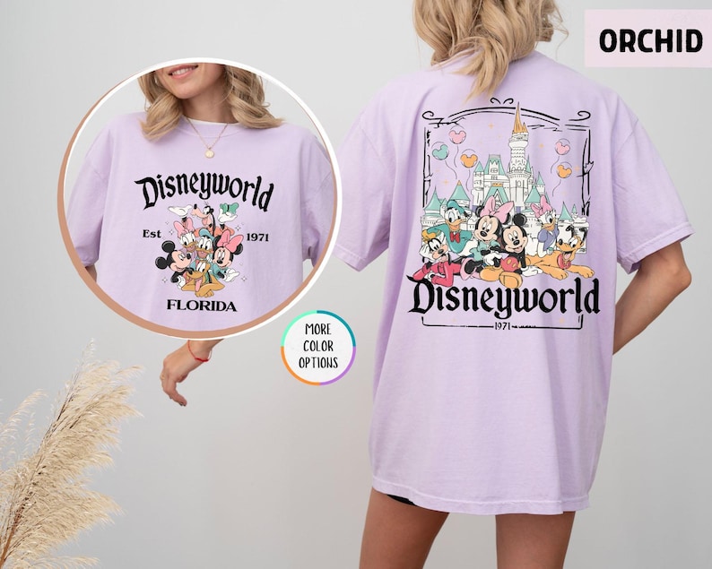 Puede incluir: Camiseta color orqu&iacute;dea con un gr&aacute;fico de Disneyworld en la parte delantera y trasera. El gr&aacute;fico frontal presenta personajes de Disney y el texto "Disneyworld Est. 1971 Florida". El gr&aacute;fico trasero muestra el castillo de Disney y personajes.