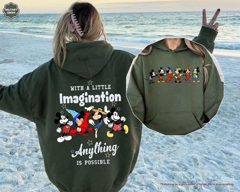 Puede incluir: Una sudadera con capucha verde oliva con un gr&aacute;fico de Mickey Mouse y sus amigos. La parte posterior de la sudadera con capucha tiene el texto "WITH A LITTLE Imagination Anything IS POSSIBLE". La parte delantera de la sudadera con capucha tiene un gr&aacute;fico m&aacute;s peque&ntilde;o de los personajes.