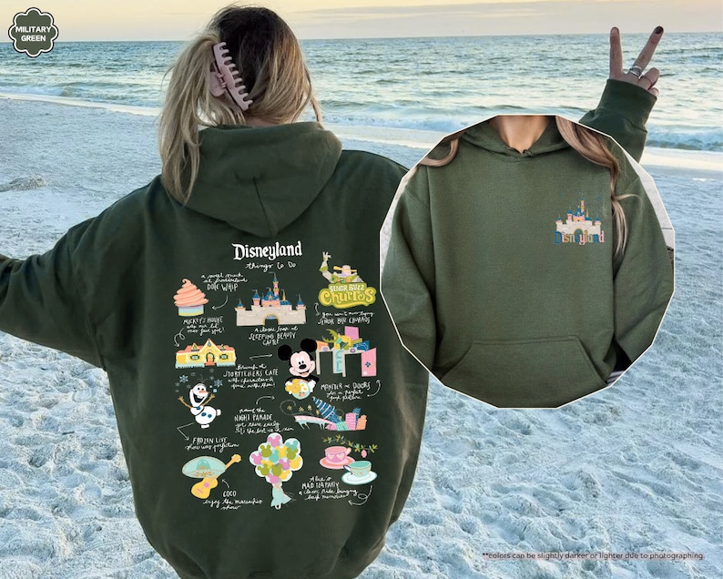 a woman wearing a green disneyland hoodie on the beach
