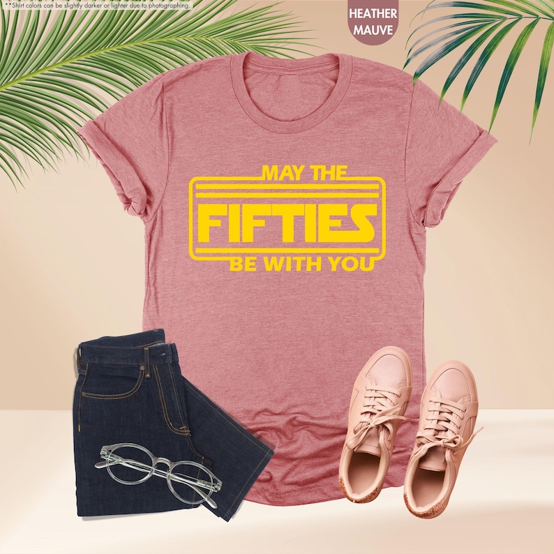 May include: A heather mauve t-shirt with a yellow graphic that says "May the Fifties Be With You".