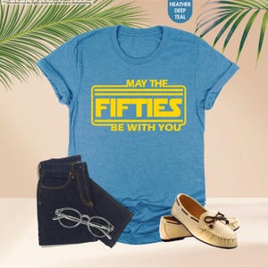 May include: A blue t-shirt with a yellow graphic that says "May the Fifties Be With You".