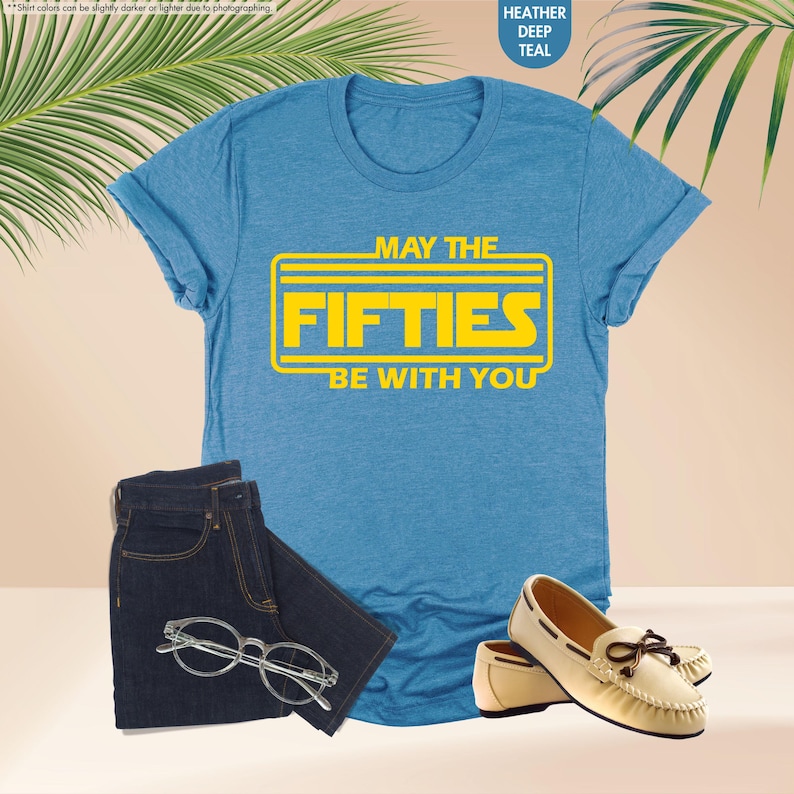 May include: A blue t-shirt with a yellow graphic that says "May the Fifties Be With You".