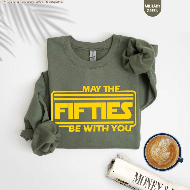 May include: A green sweatshirt with the text "May the Fifties Be With You" in a yellow Star Wars-inspired font.