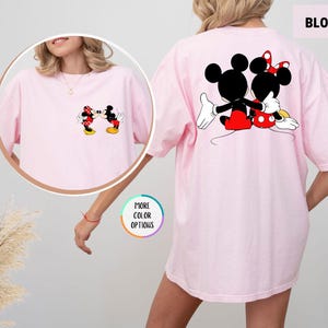 May include: Pale pink t-shirt with a cartoon image of Mickey and Minnie Mouse kissing on the front and back. The back of the shirt has a larger image of the couple. The word "BLOSSOM" is printed on the top right.