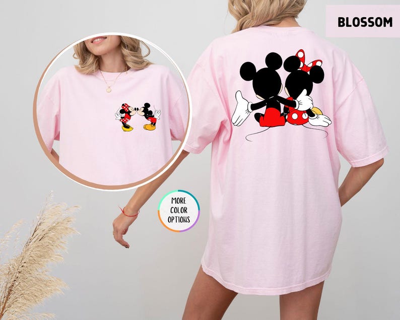 May include: Pale pink t-shirt with a cartoon image of Mickey and Minnie Mouse kissing on the front and back. The back of the shirt has a larger image of the couple. The word "BLOSSOM" is printed on the top right.