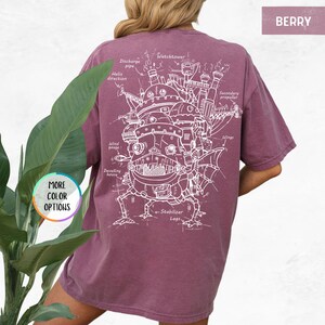 Op de afbeelding: Bessenkleurig T-shirt met een gedetailleerde witte schematische weergave van een fantastische bewegende structuur, met labels zoals "Watchtower" en "Stabilizer Legs". De tekst "MORE COLOR OPTIONS" en "BERRY" staan ook op het shirt.