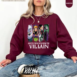 a woman sitting on a stool wearing a sweatshirt