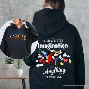 Puede incluir: Sudadera con capucha negra con un gr&aacute;fico colorido de personajes de Disney. La parte trasera de la sudadera tiene el texto "With a Little Imagination Anything is Possible". La sudadera tiene una capucha con cord&oacute;n.