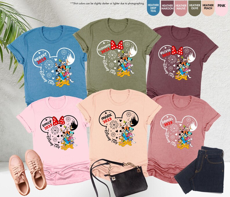 May include: Six different color t-shirts with a white Mickey Mouse head design. Each shirt has a name and year printed on it. The shirts say "Robert 2025", "Elizabeth 2025", "Olivia 2025", "Emily 2025", "Mark 2025", and "Daniel 2025".