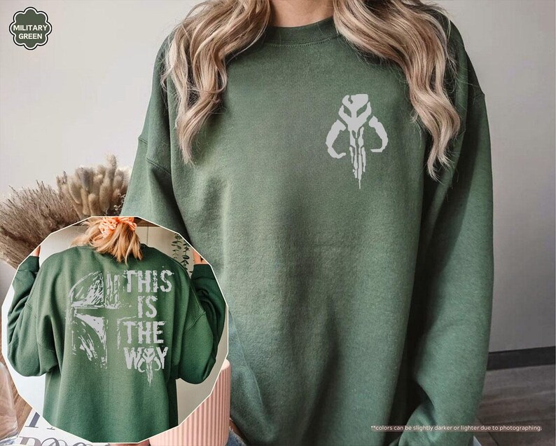 May include: A green sweatshirt with a white Mandalorian symbol on the front and the text "This is the way" on the back.