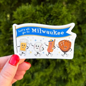 May include: A white sticker shaped like a pennant flag featuring a blue banner with the text Let's all go to Milwaukee. Below the text are four cartoon characters: a beer mug, a baseball, a hot dog with a baseball bat, and a baseball glove.
